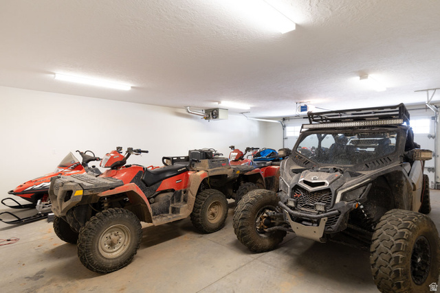 382 Ridgeview Street, Unit 8 & 9 Brian Head, UT 84719 - Photo 47 of 52 Spacious garage featuring a concrete floor, white walls, multiple fluorescent light fixtures, and a roll-up garage door with window inserts