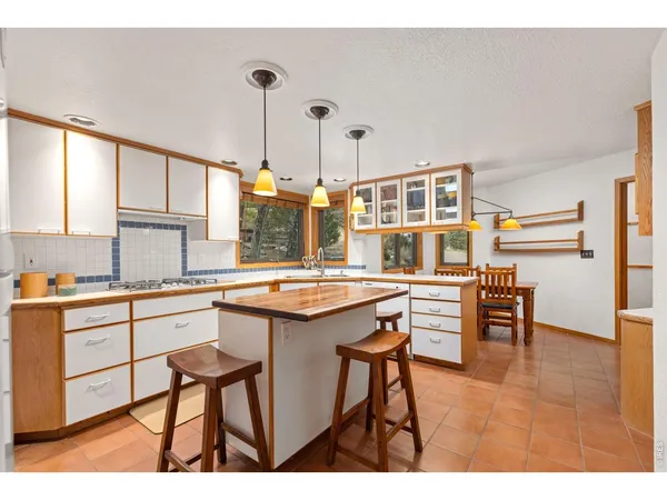 a open kitchen with stainless steel appliances granite countertop a stove top oven a sink a dining table and chairs with wooden floor