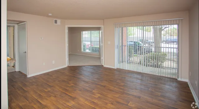 a view of a big room with wooden floor and windows