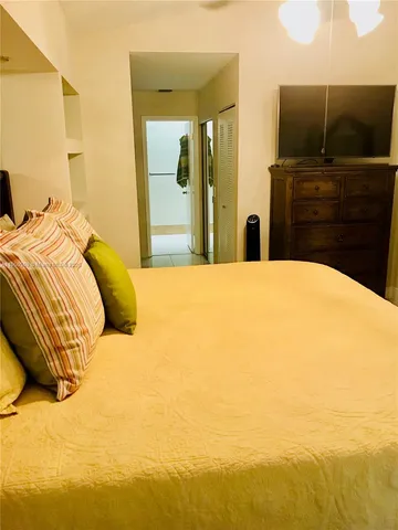 a bedroom with a bed with flat screen tv and dresser