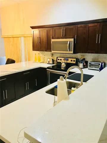 a kitchen with stainless steel appliances a sink a stove a microwave a sink a refrigerator and cabinets