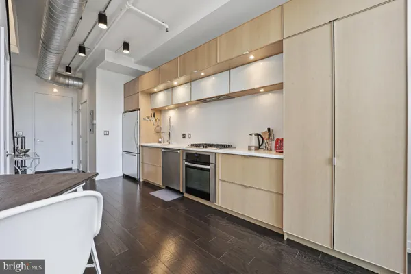 a kitchen with stainless steel appliances a refrigerator a stove a sink and white cabinets with wooden floor