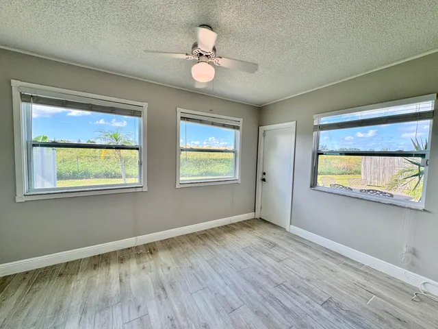 a view of an empty room with window and wooden floor