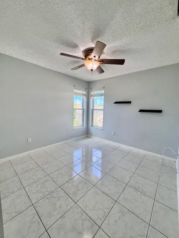 a view of an empty room with a window and a chandelier fan