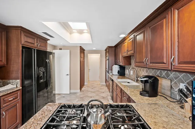 a kitchen with stainless steel appliances granite countertop a stove a sink and a refrigerator