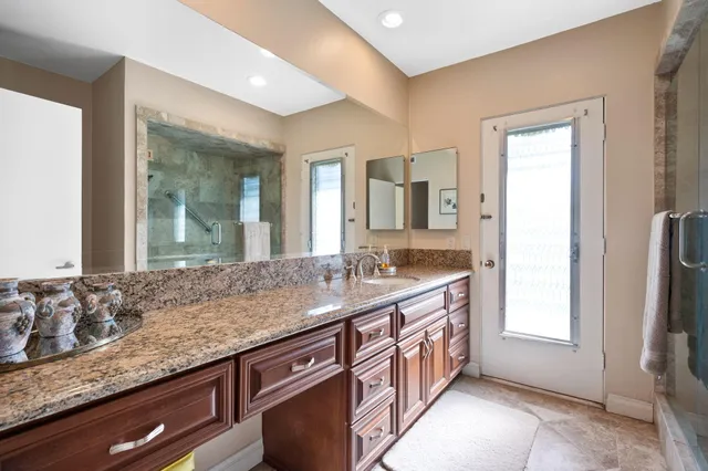 a bathroom with a granite countertop sink and a large mirror