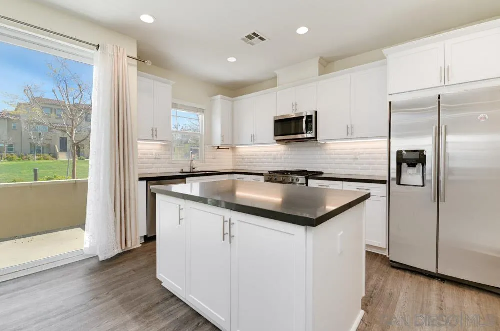 4314 Star Path Way, Unit 1 Oceanside, CA 92056 - Photo 7 of 40 a kitchen with kitchen island granite countertop a sink and refrigerator