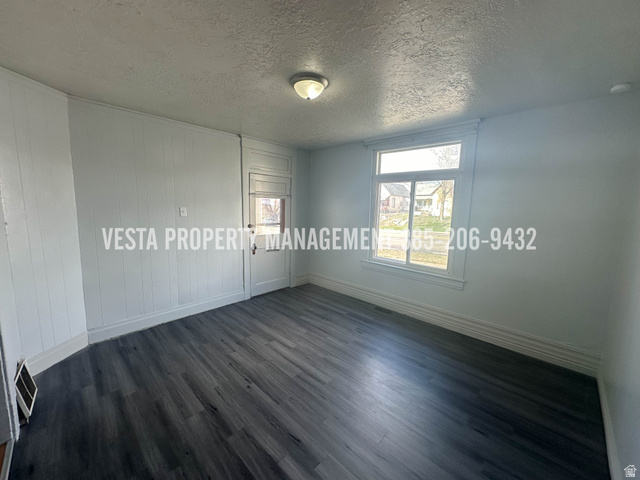 471 East 22nd Street Ogden, UT 84401 - Photo 3 of 12 Unfurnished bedroom with a textured ceiling, dark wood-style flooring, and wooden walls