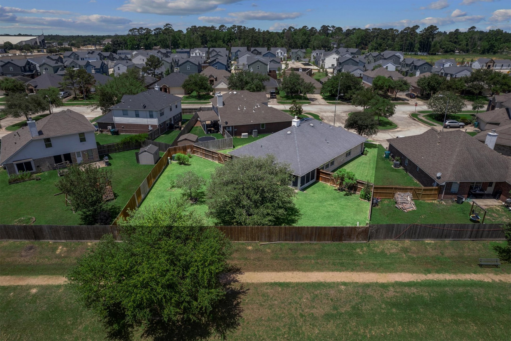 2507 Grayfeather Court Spring, TX 77388 - Photo 32 of 37 Well-maintained property featuring a spacious backyard, enclosed by a wooden fence, with a central tree and green lawn.