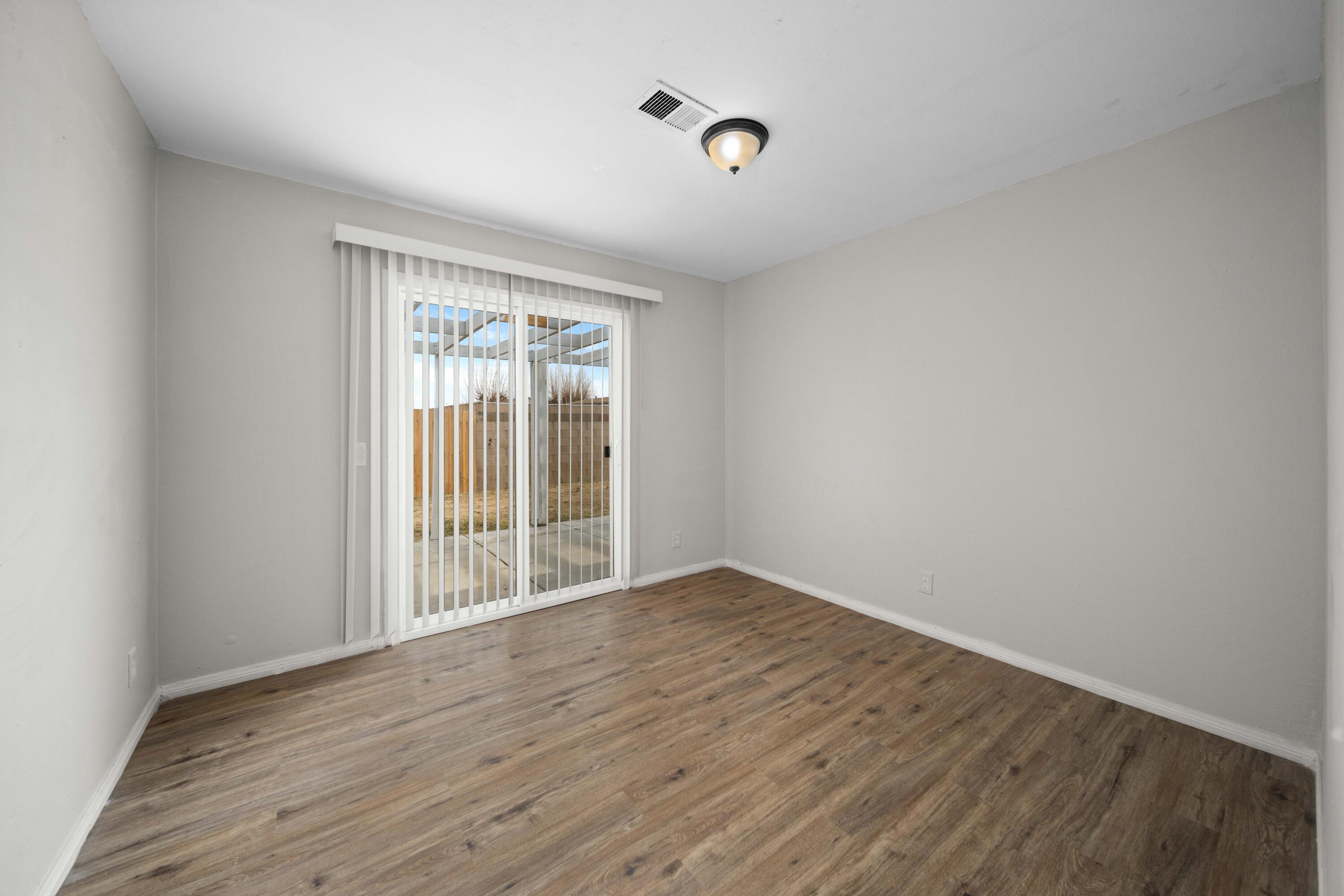 3360 West Roxbury Street Rosamond, CA 93560 - Photo 17 of 23 a view of an empty room with wooden floor and a window