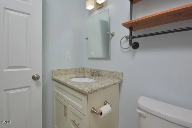 a bathroom with a granite countertop sink and a toilet