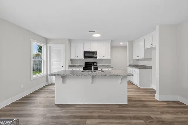 a kitchen with stainless steel appliances granite countertop a sink a stove a refrigerator cabinets and a window