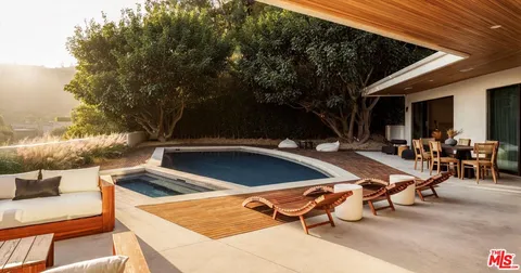 a view of a swimming pool with chairs in front of a house