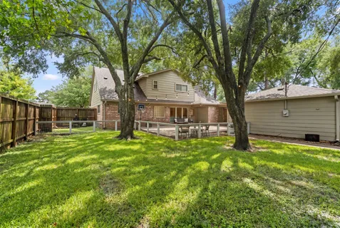 a view of a backyard with wooden fence and a large tree