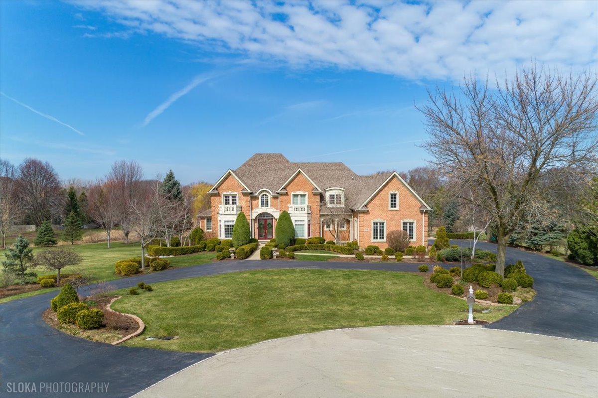 a view of a big house with a big yard and large trees