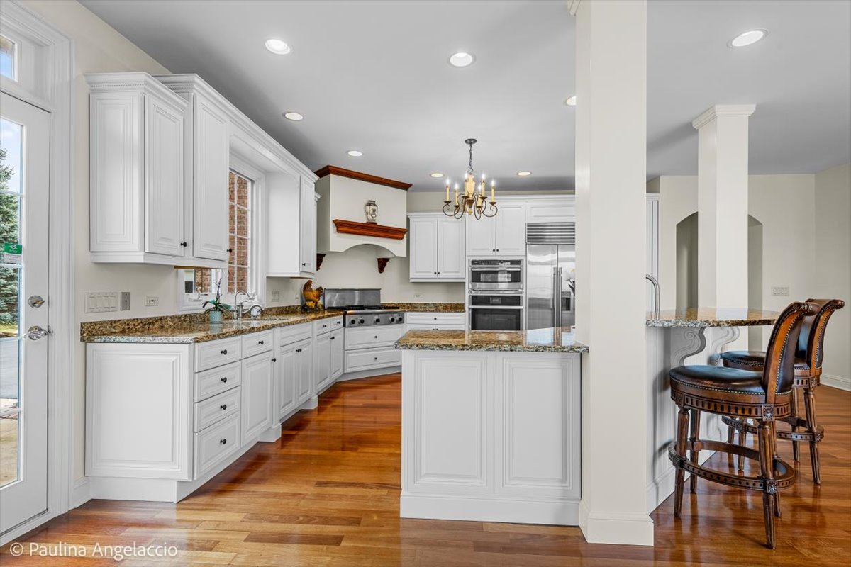 1175 Woodburn Court Inverness, IL 60067 - Photo 17 of 68 a kitchen with stainless steel appliances kitchen island granite countertop a table and chairs in it