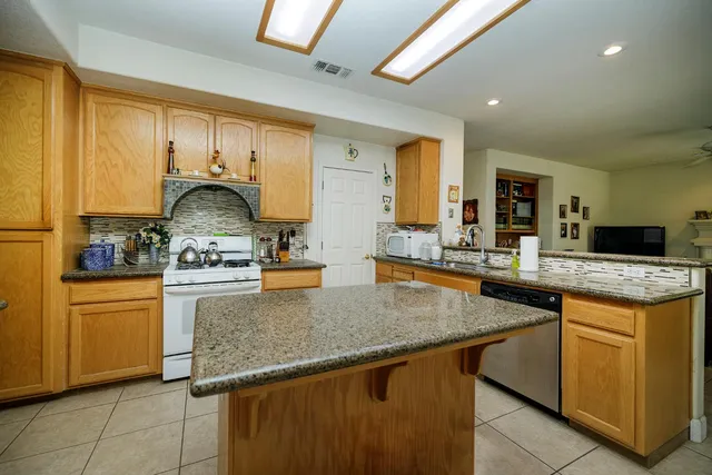 a kitchen with stainless steel appliances granite countertop a refrigerator a stove and a sink with granite countertops