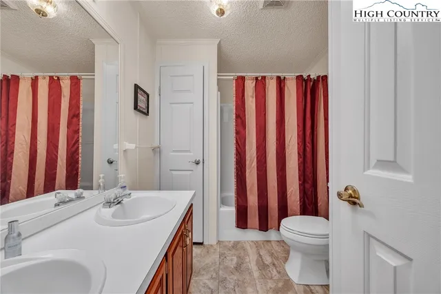 a bathroom with a sink a toilet and shower curtain