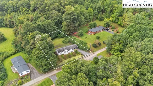 an aerial view of residential house with outdoor space and trees all around