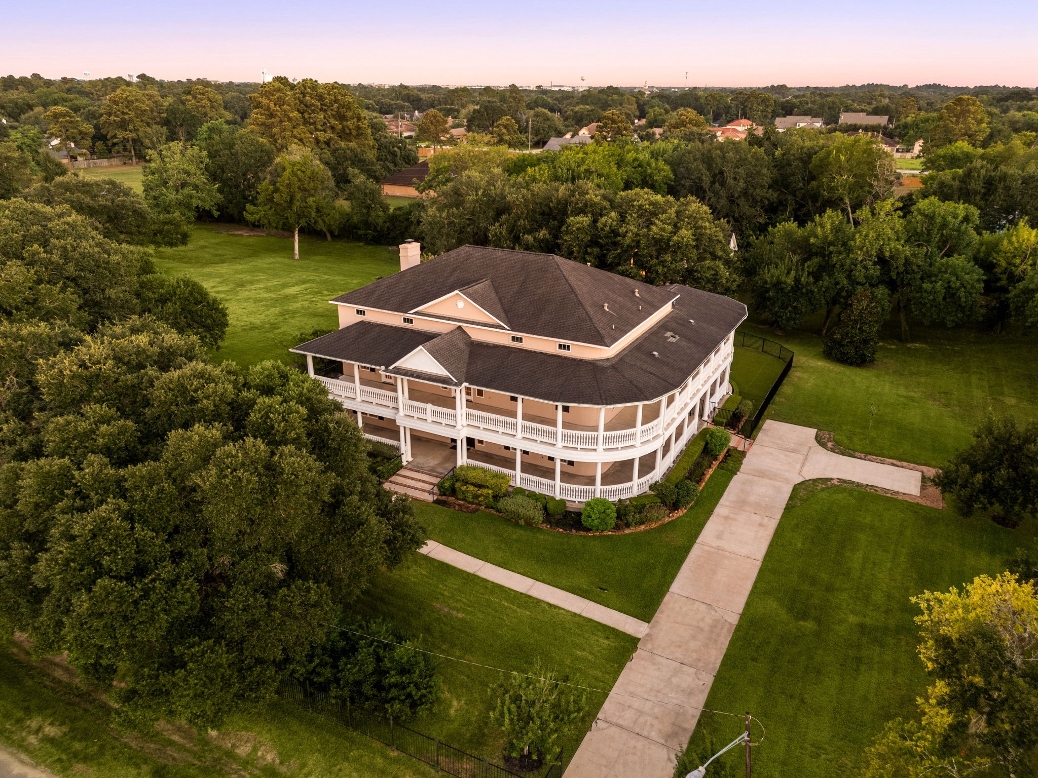6039 Franz Road Katy, TX 77493 - Photo 45 of 49 From above at twilight, the home's full wraparound veranda and expansive grounds come into view, framed by mature oaks and manicured lawn.
