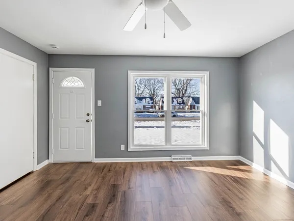 an empty room with wooden floor and windows