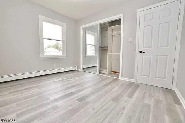 an empty room with wooden floor cabinet and windows