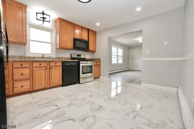 a large kitchen with stainless steel appliances granite countertop a stove top oven a sink dishwasher and white cabinets with wooden floor