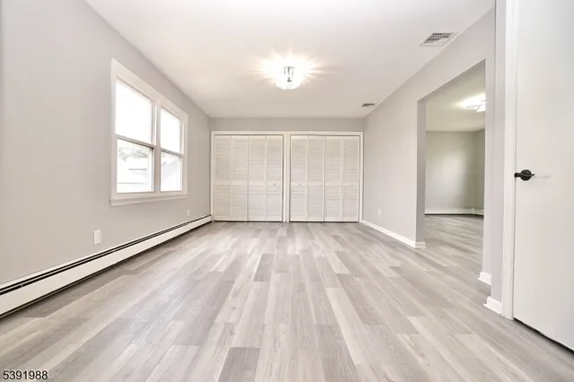 an empty room with wooden floor and windows
