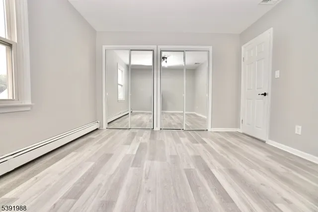 a view of an empty room with wooden floor and windows