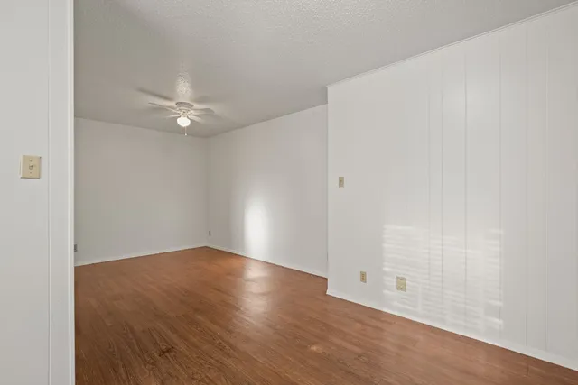an empty room with wooden floor and fan