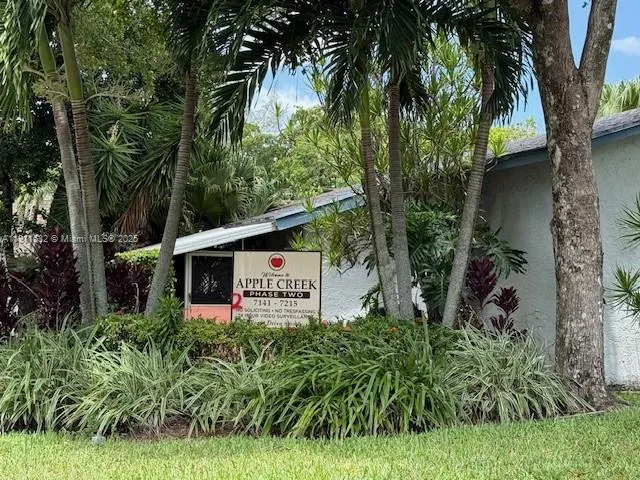 a sign that is sitting in front of a house with plants