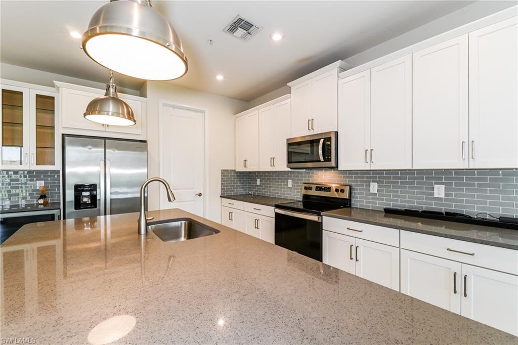 4721 Arboretum Circle, Unit 201 Naples, FL 34112 - Photo 6 of 26 a kitchen with granite countertop a stove a sink a counter space and cabinets