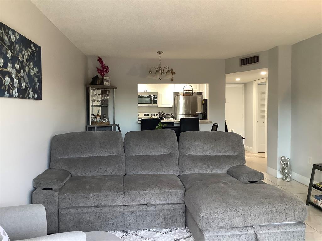 4174 Inverrary Drive, Unit 309 Lauderhill, FL 33319 - Photo 9 of 21 a living room with couches and a dining table with white walls