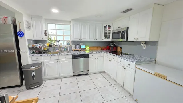 a kitchen with cabinets appliances a sink and a window