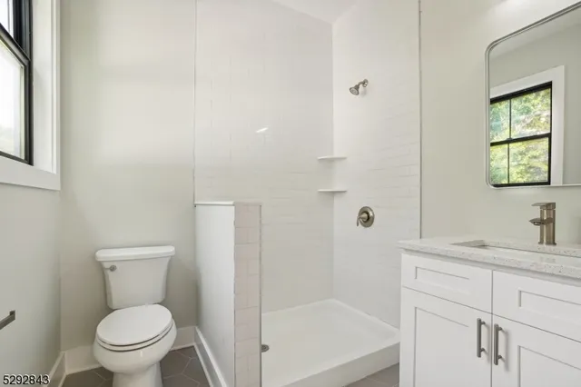 a bathroom with a granite countertop toilet a sink a mirror and a shower