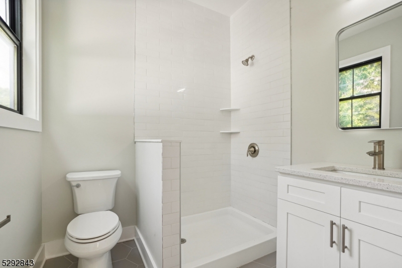 29 Arlington Road, Unit 1 Cranford, NJ 07016 - Photo 12 of 15 a bathroom with a granite countertop toilet a sink a mirror and a shower
