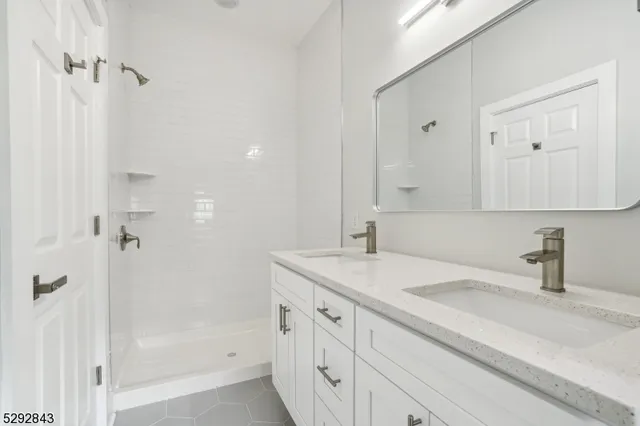 a bathroom with a sink double vanity granite tub shower and a mirror