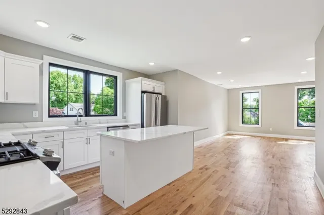 a kitchen with stainless steel appliances a sink a stove a refrigerator cabinets and a window