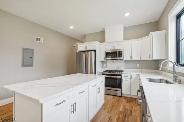 a kitchen with granite countertop white cabinets and stainless steel appliances