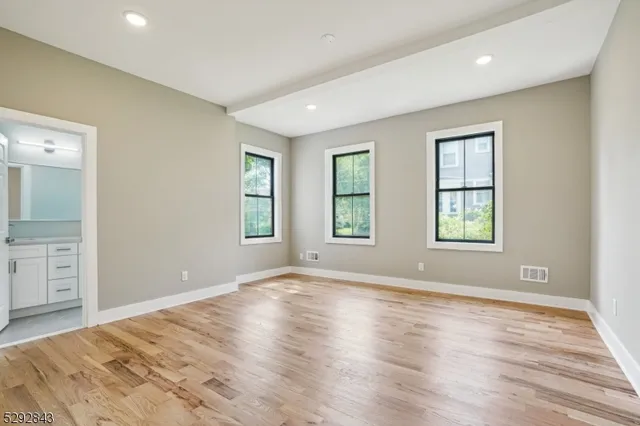 a view of an empty room with window and wooden floor