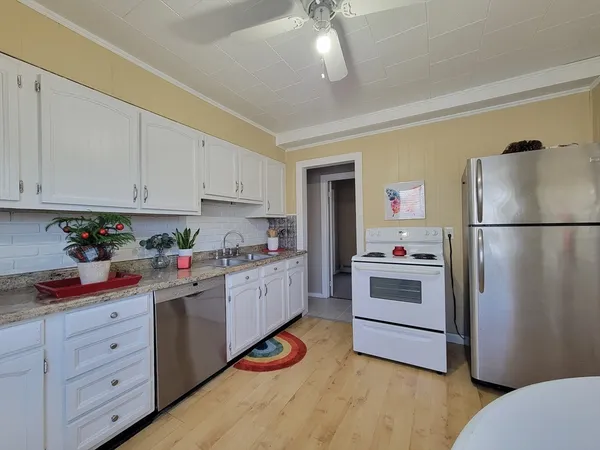 a kitchen with refrigerator a stove a sink dishwasher and white cabinets with wooden floor