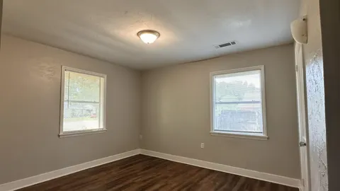 a view of a big room with wooden floor and windows