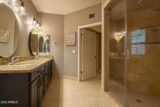 a bathroom with a granite countertop sink a large mirror and a shower
