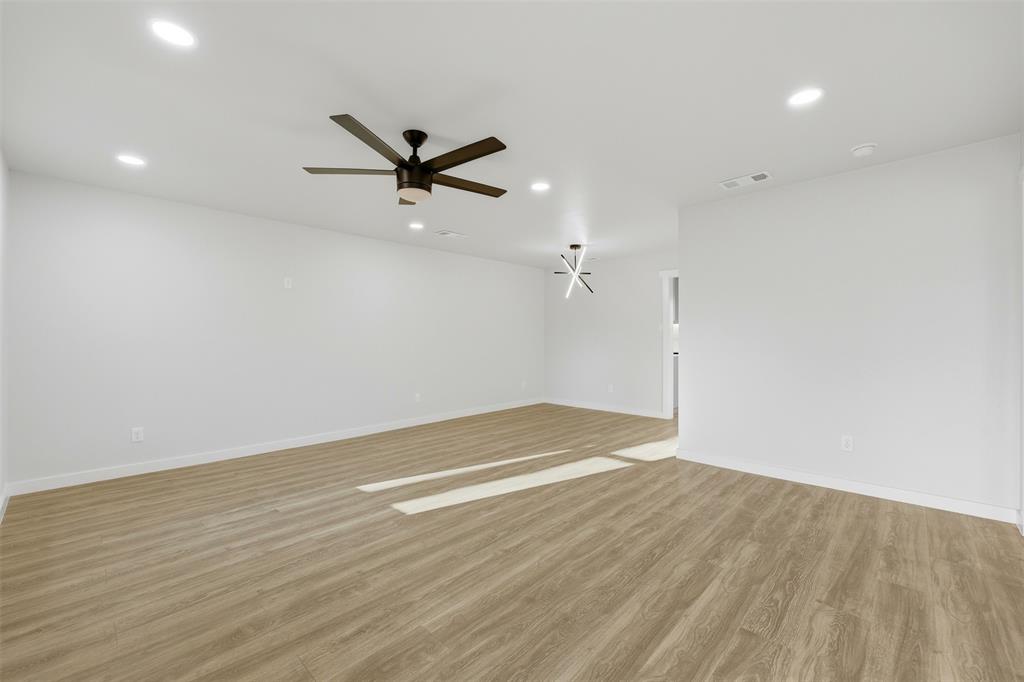 502 Madison Street Cleburne, TX 76033 - Photo 5 of 30 an empty room with wooden floor and a ceiling fan