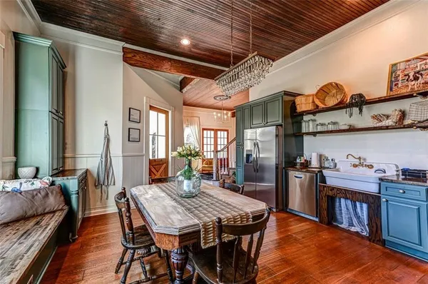 a dining room with stainless steel appliances granite countertop a table chairs and wooden floor