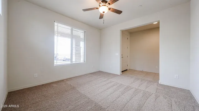an empty room with chandelier fan and windows