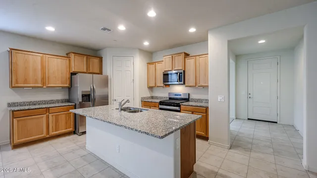 a kitchen with granite countertop kitchen island stainless steel appliances a stove sink microwave and cabinets