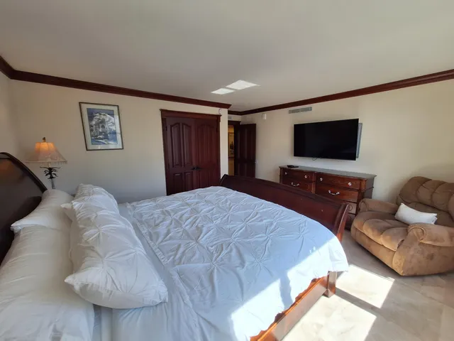a spacious bedroom with a bed and a lamp on dresser