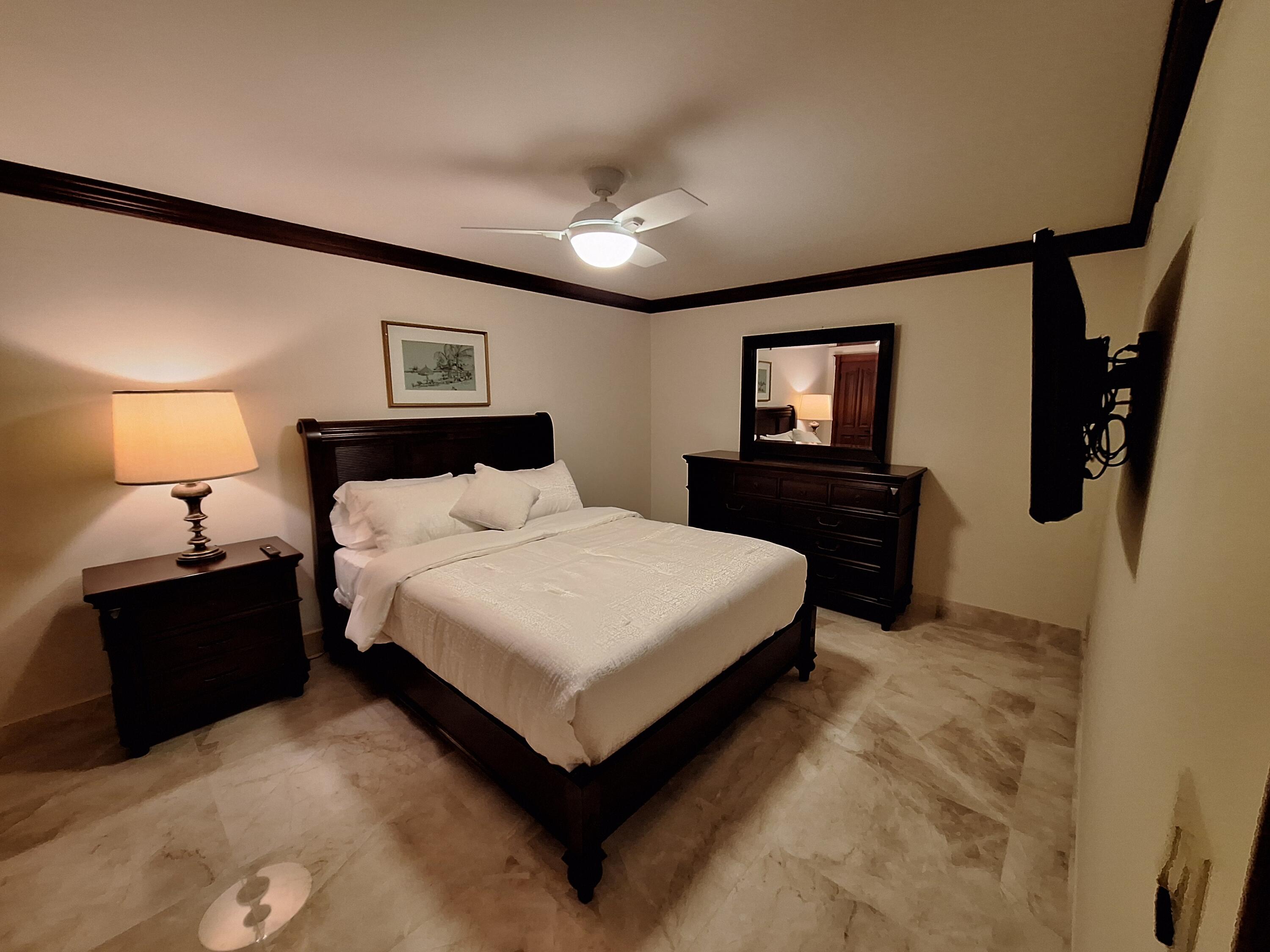 3400 North Ocean Drive, Unit PH2 Singer Island, FL 33404 - Photo 37 of 38 a spacious bedroom with a bed and a lamp on dresser