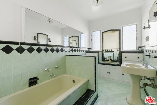 a bathroom with a bathtub sink mirror and a shower